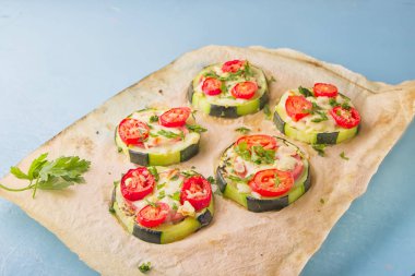 Biber, domates, peynir ve maydanoz parşömen kağıt üzerine açık mavi renkli üzerinde pizza sağlıklı, besleyici kabak küçük yuvarlak.