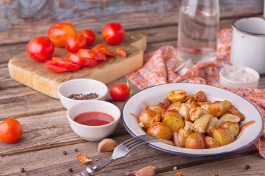Geleneksel çiftçiler gıda. Havuç, soğan ve tavuk göğsü parçaları ahşap arka plan üzerinde eski metal plaka ile kavrulmuş kırmızı patates. Kırmızı domates ve temiz su bir bardak ile görev yaptı. Leziz yemek.