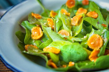 Sebze salatası. Roka, pişmiş dilimlenmiş havuç, zeytinyağında koyu ahşap arka plan üzerinde metal plaka ile sağlıklı yemek. Sağlıklı bir diyet yemek