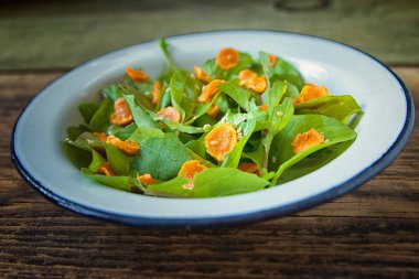 Sebze salatası. Roka, pişmiş dilimlenmiş havuç, zeytinyağında koyu ahşap arka plan üzerinde metal plaka ile sağlıklı yemek. Sağlıklı bir diyet yemek