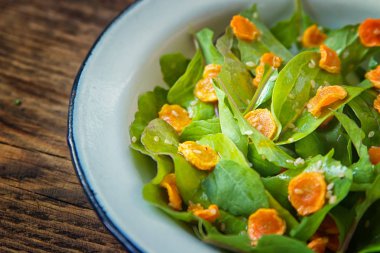 Sebze salatası. Roka, pişmiş dilimlenmiş havuç, zeytinyağında koyu ahşap arka plan üzerinde metal plaka ile sağlıklı yemek. Sağlıklı bir diyet yemek