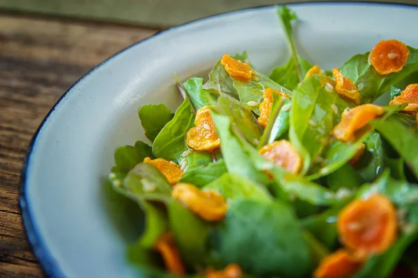 Sebze salatası. Roka, pişmiş dilimlenmiş havuç, zeytinyağında koyu ahşap arka plan üzerinde metal plaka ile sağlıklı yemek. Sağlıklı bir diyet yemek