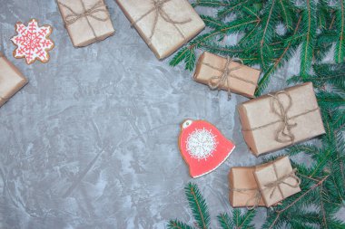 Dekoratif gingerbread, Ladin şube ve hediye kutuları gri çimento zemin tebrik kartı. Yılbaşı yeni yıl arka plan yükü. Yukarıdan görüntüleyin. Kopya alanı.