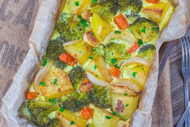 Brokoli havuç, patates, beyaz soğan ve sarımsak kaşar ile güveç pişirme çanağı ahşap arka plan üzerinde içinde yumurta. Üstten görünüm, kopya alanı.