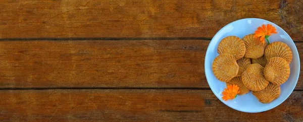在一个蓝色的盘子里放糖饼干 在木制的背景上有金盏花 长的格式 — 图库照片