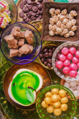 Çay molası lezzetli tatlım pasta ile dekore edilmiş bir yeşil elma şeklinde ve çok renkli küçük şekerlemeler çeşitli. Bir kompozisyon testi ile bakır ve kil levha. Arap kavramı.