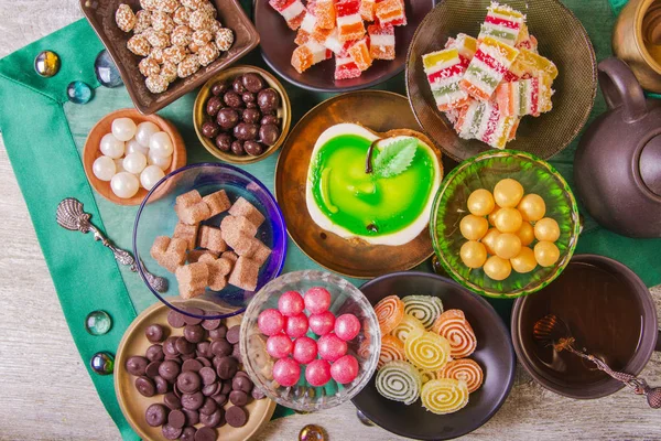 茶歇与美味的蜂蜜蛋糕装饰在一个绿色的苹果和各种五颜六色的小糖果的形式 铜和粘土板在组合物与水罐 阿拉伯概念 — 图库照片