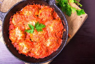 Domates sosu sarımsak ve maydanoz koyu kahverengi ahşap arka plan üzerinde bir demir tavada köfte. Üstten görünüm. Kopya alanı.