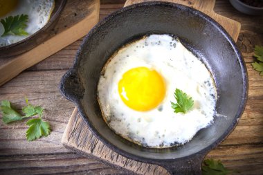 İki küçük kızartma tavada kızarmış yumurta tohumlar, jambon, domates ve maydanoz ile ev yapımı ekmek ile servis edilir. Lezzetli yemekler.