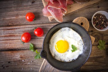 İki küçük kızartma tavada kızarmış yumurta tohumlar, jambon, domates ve maydanoz ile ev yapımı ekmek ile servis edilir. Lezzetli yemekler.