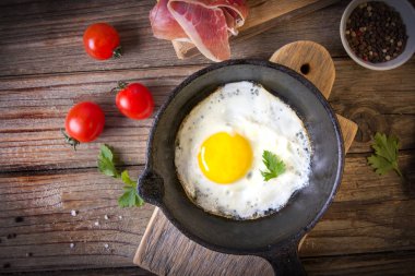 İki küçük kızartma tavada kızarmış yumurta tohumlar, jambon, domates ve maydanoz ile ev yapımı ekmek ile servis edilir. Lezzetli yemekler.