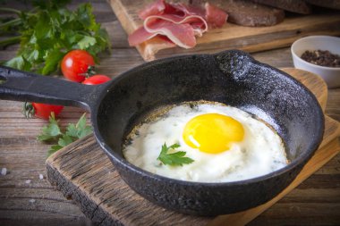 İki küçük kızartma tavada kızarmış yumurta tohumlar, jambon, domates ve maydanoz ile ev yapımı ekmek ile servis edilir. Lezzetli yemekler.