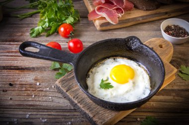 İki küçük kızartma tavada kızarmış yumurta tohumlar, jambon, domates ve maydanoz ile ev yapımı ekmek ile servis edilir. Lezzetli yemekler.