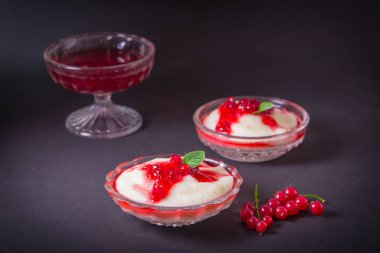 Puding irmik bir cam kase Frenk üzümü şurubu ve çilek ile üzerinden. Karanlık bir arka plan üzerinde.