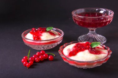 Puding irmik bir cam kase Frenk üzümü şurubu ve çilek ile üzerinden. Karanlık bir arka plan üzerinde.