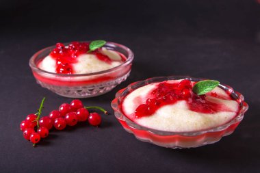 Puding irmik bir cam kase Frenk üzümü şurubu ve çilek ile üzerinden. Karanlık bir arka plan üzerinde.