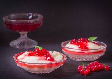 Puding irmik bir cam kase Frenk üzümü şurubu ve çilek ile üzerinden. Karanlık bir arka plan üzerinde.