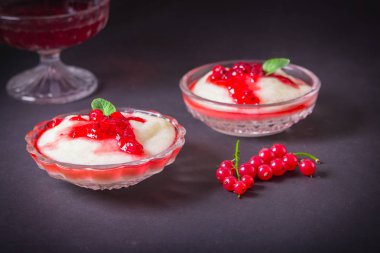 Puding irmik bir cam kase Frenk üzümü şurubu ve çilek ile üzerinden. Karanlık bir arka plan üzerinde.