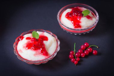 Puding irmik bir cam kase Frenk üzümü şurubu ve çilek ile üzerinden. Karanlık bir arka plan üzerinde.