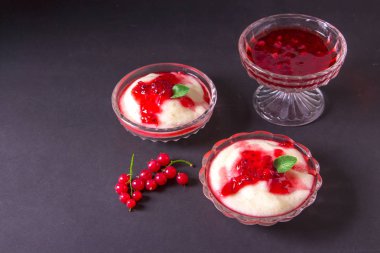 Puding irmik bir cam kase Frenk üzümü şurubu ve çilek ile üzerinden. Karanlık bir arka plan üzerinde.