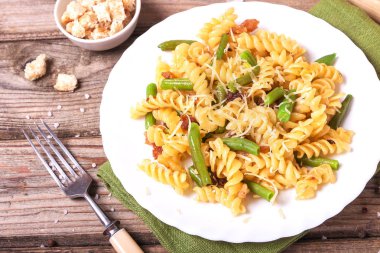 Traditional Italian Sicilian fusilli pasta with bread crumbs and green beans, sprinkled with cheese in a white plate on a wooden background. Tasty food. clipart