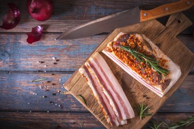 Koyu zeminde tuzlu pastırma parçaları. Baharatlar ile sağlıklı gıda, otlar vintage masada biberiye dekore edilmiştir. Yağ, domuz yağı, donyağı, yağ. Üstte görüntü