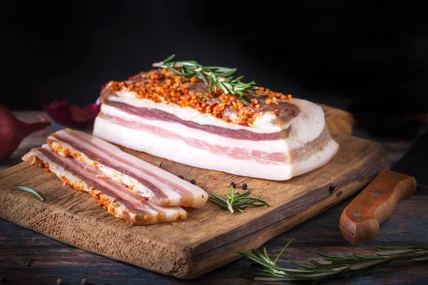 Koyu zeminde tuzlu pastırma parçaları. Baharatlar ile sağlıklı gıda, otlar vintage masada biberiye dekore edilmiştir. Yağ, domuz yağı, donyağı, yağ