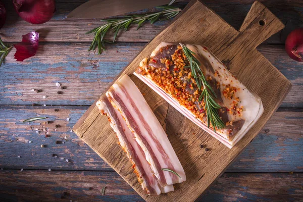 Koyu zeminde tuzlu pastırma parçaları. Baharatlar ile sağlıklı gıda, otlar vintage masada biberiye dekore edilmiştir. Yağ, domuz yağı, donyağı, yağ. Üstte görüntü