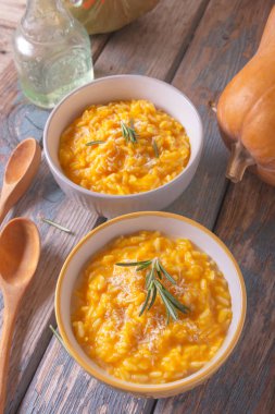 Ahşap arka plan üzerinde bir kase parmesan peyniri ile lezzetli kabak risotto. Rustik stil