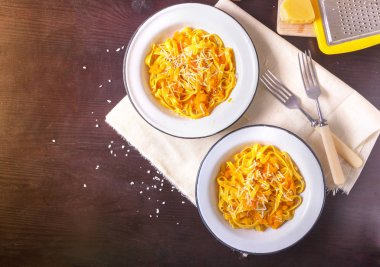 Koyu arka plan üzerinde beyaz tabakta kabak kremaparmesan peyniri ile kabak tagliatelle makarna