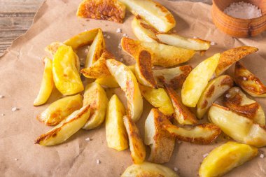 Gevrek altın derin kızarmış, patates kızartması sıcak patates, kızartma ve yenmeye hazır, gerçekten nefis. Bir rustik ahşap arka plan üzerinde zanaat kağıt üzerinde Patates