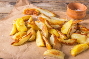 Gevrek altın derin kızarmış, patates kızartması sıcak patates, kızartma ve yenmeye hazır, gerçekten nefis. Bir rustik ahşap arka plan üzerinde zanaat kağıt üzerinde Patates