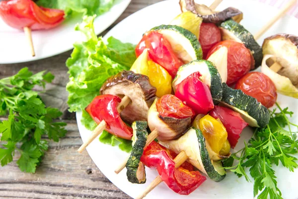 Sağlıklı sebze şiş. Organik sebze şiş kebap patlıcan, biber, kabak, domates ve soğan tahtası ile marul ve maydanoz ahşap arka plan üzerinde kızarmış.