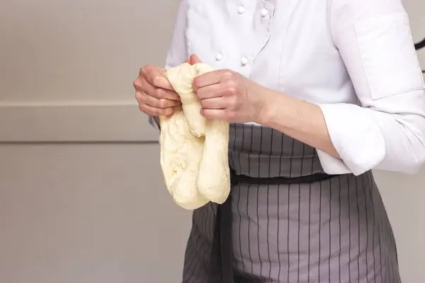 Baking concept. Hard working women prepares pastry by himself, kneads dough on wooden counter with flour and rolling pin. Women cook bakes bread or delicious bun or pasta — Stock Photo, Image