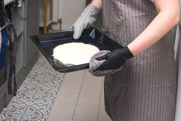 Жінка готує на кухні, кладе пиріг в духовку — стокове фото