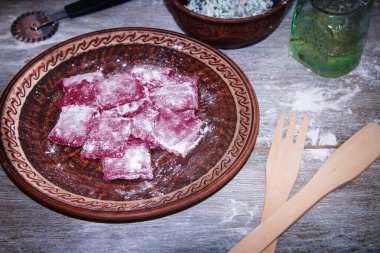 Ahşap rustik arka plan üzerinde, bir tabakta peynir ve maydanoz ile ev yapımı çiğ pembe pancar makarna ravioli