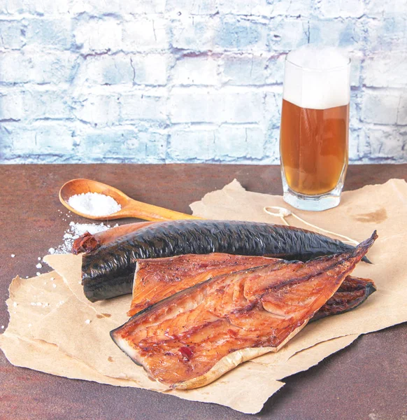 Gerookte makreelfilets op ambachtelijk papier met een glas bier op een rustieke roestige metalen tafel — Stockfoto
