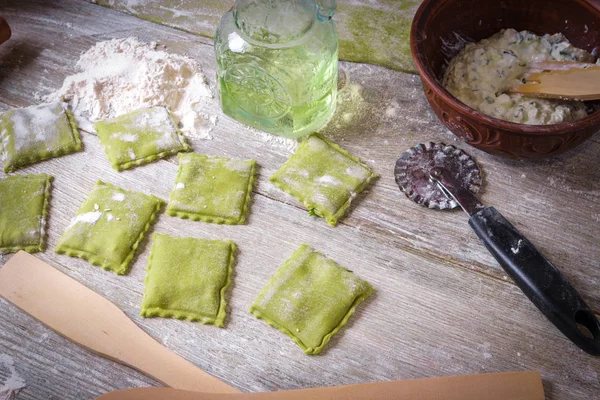 Homemade raw green spinach ravioli with ricotta cheese and parsley on a wooden rustic background