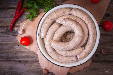 Sebzeli bir tabakta çiğ taze beyaz sosis. Weisswurst bir yığın halinde. Dilimlenmiş dana eti ve domuz pastırması yapılan geleneksel Bavyera veya Münih beyaz sosis. Oktoberfest konsepti