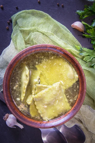 Ispanak yeşil mantı ve yeşil maydanoz ile sıcak suyu. İtalyan mutfağı. Karanlık bir arka plan üzerinde