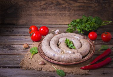 Sebzeli bir tabakta çiğ taze beyaz sosis. Weisswurst bir yığın halinde. Dilimlenmiş dana eti ve domuz pastırması yapılan geleneksel Bavyera veya Münih beyaz sosis. Oktoberfest konsepti