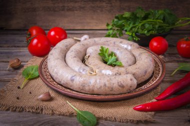 Sebzeli bir tabakta çiğ taze beyaz sosis. Weisswurst bir yığın halinde. Dilimlenmiş dana eti ve domuz pastırması yapılan geleneksel Bavyera veya Münih beyaz sosis. Oktoberfest konsepti