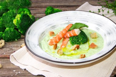 Rustik ahşap arka plan üzerinde bir tabakta karides ile Brokoli yeşil krema çorbası. Temiz gıda, sağlıklı beslenme kavramı.