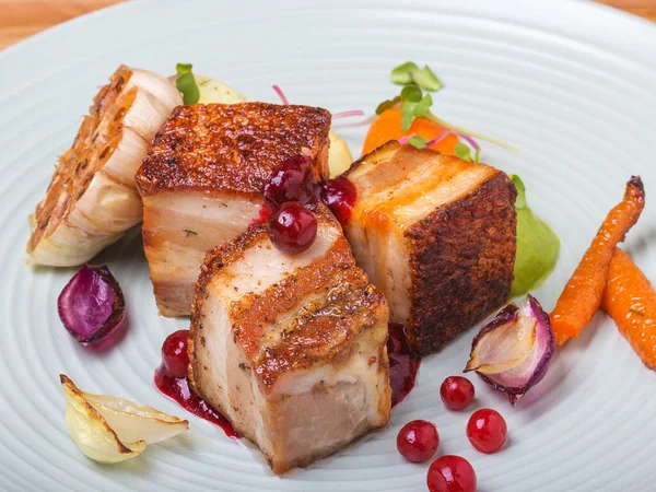 Kızılcık soslu domuz eti, fırında sarımsak ve patates püresi, havuç ve bezelyeyle süslenmiş bezelye. Lezzetli yemek..