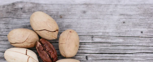Pecan Nuts on wooden background, top view with copyspace. Close up veiw of nuts. Banner size with copy space.
