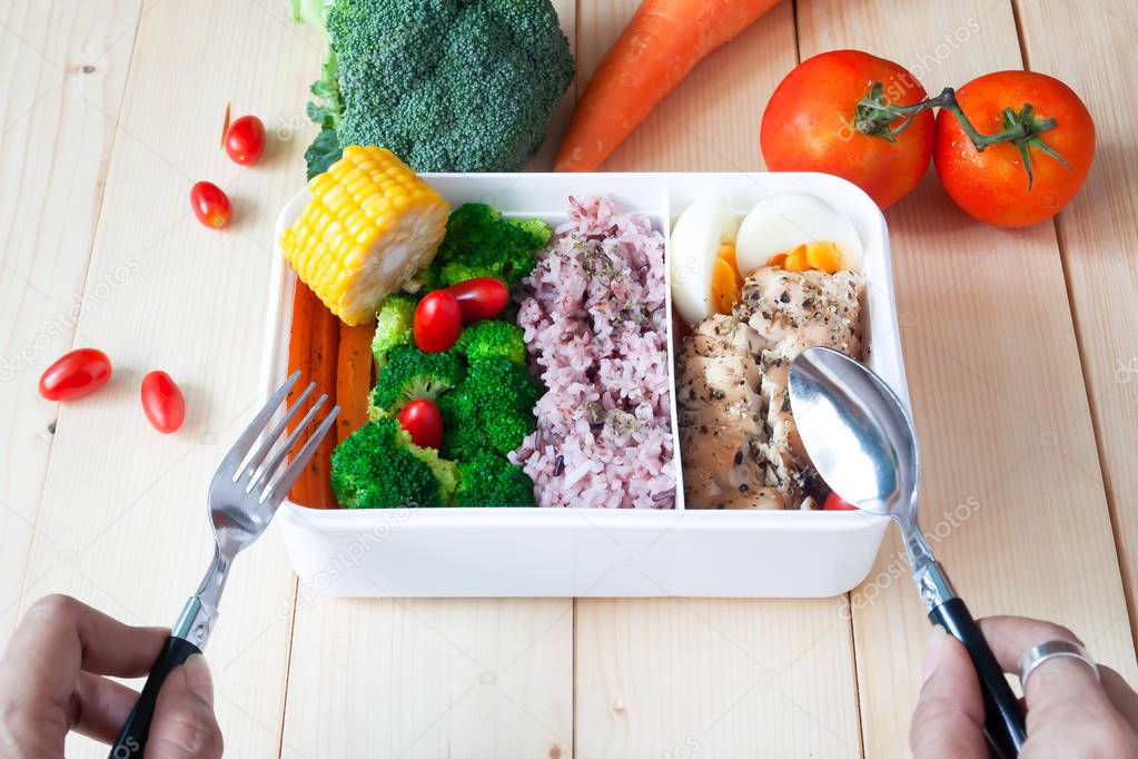 Healthy meal in lunch box with vegetables, carrot, broccoli, rice berry, chicken breast and boiled egg, Woman eating healthy lunch box