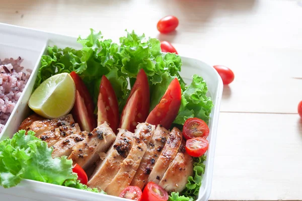 Close up of lunch box, Grilled chicken breast with lettuce, tomatoes, lime and rice berry. Healthy lifestyle