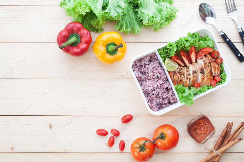 Lunch box, grilled chicken breast with tomatoes, lettuce and steam rice. Top view on wooden background, Healthy lifestyle concept