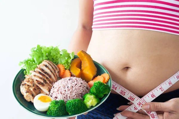 Kadın giyiyor spor sutyen belly fat ve ölçme ile teyp sağlıklı yiyecek çanak tutuyor. Sağlıklı ve diyet kavramı