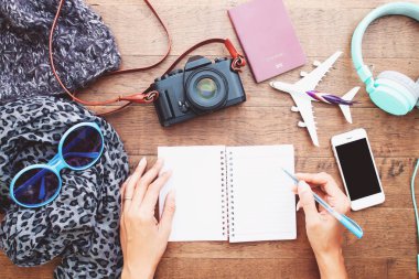 Görünüm kadının elleri boş defter günlüğü, akıllı telefon, kamera ve pasaport ile top. Seyahat yaşam tarzı kavramı